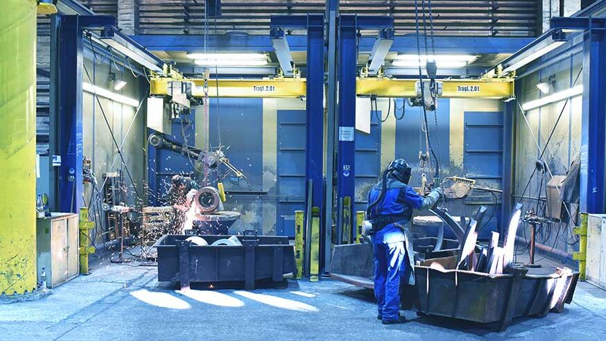 Arbeiter in einer Industriehalle - schweißen und flexen von Werkstücken/ Gussteilen aus Metall