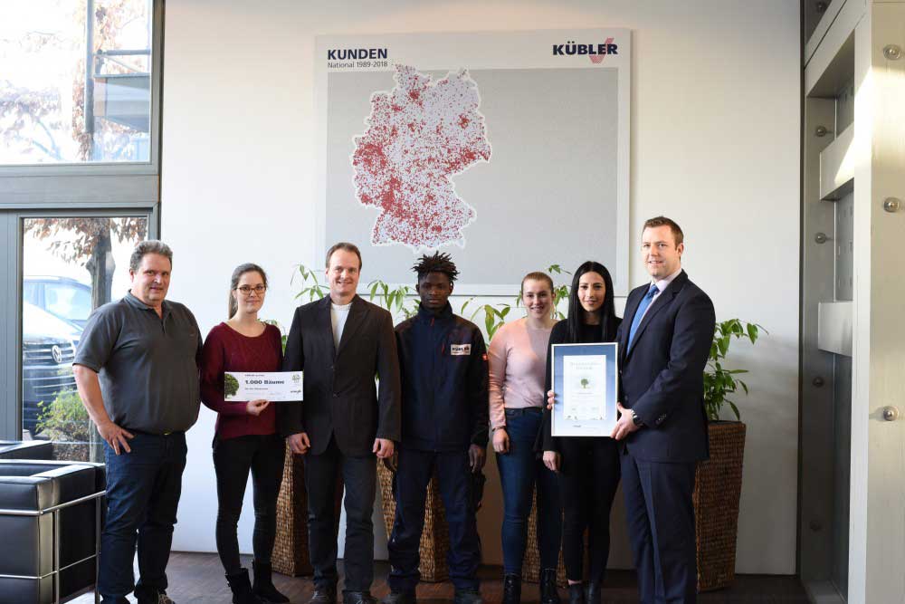 Gruppenfoto der Mitarbeiter der Firma KÜBLER GmbH mit einer Auszeichnung der Baumspendenaktion
