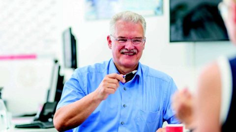 Lächelnder Mann mit Brille im Büro.