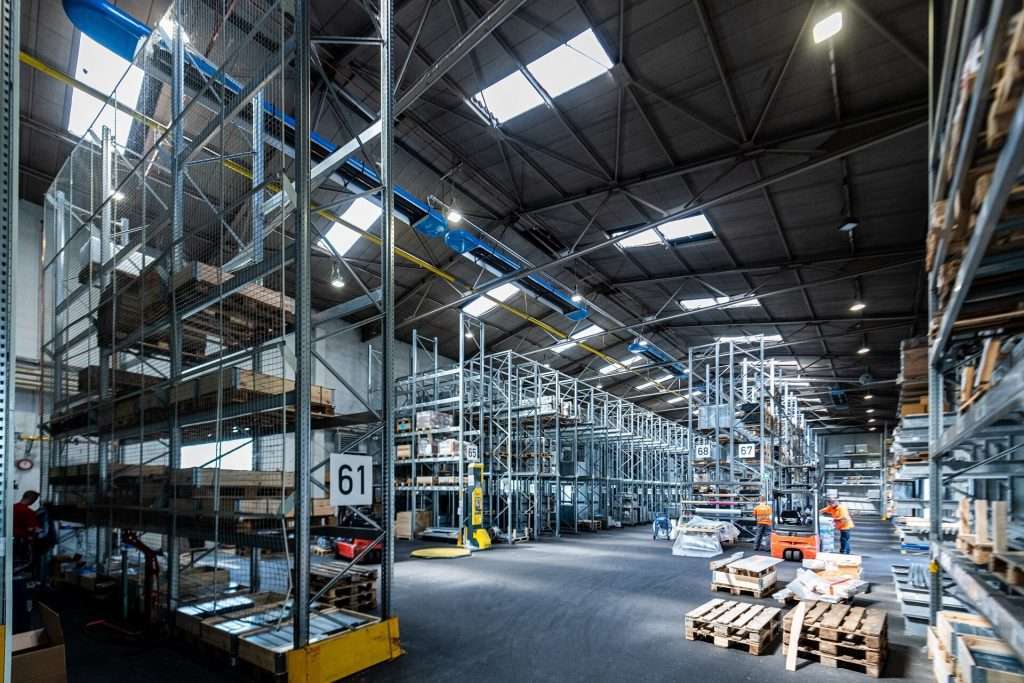 Workers in a modern warehouse with shelves and forklifts