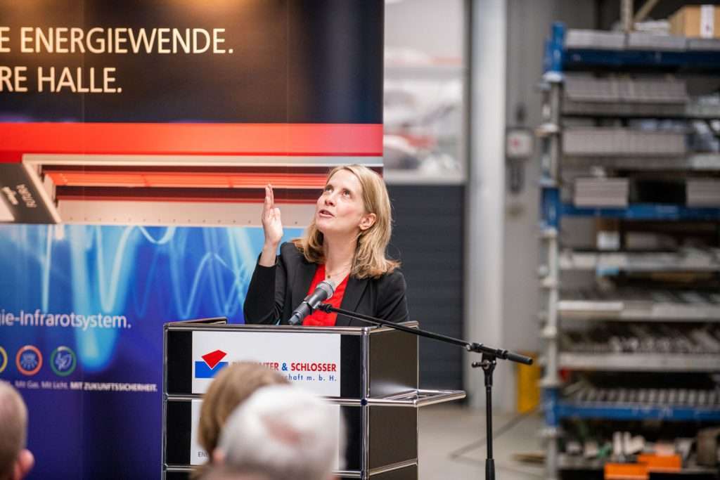 Frau spricht bei einer Industrieveranstaltung am Rednerpult.