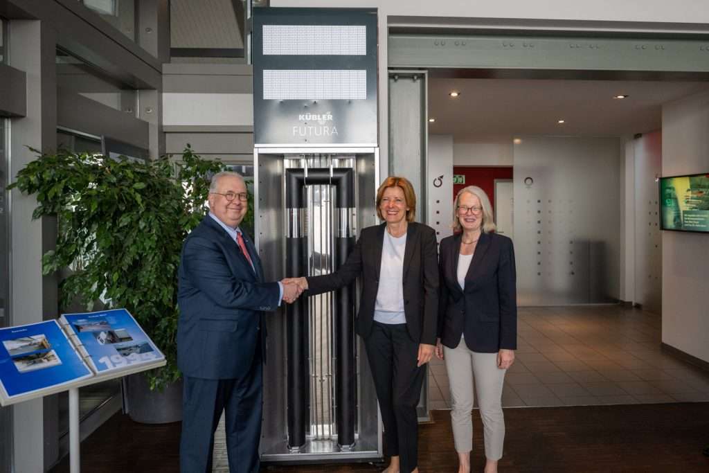 Drei Personen vor Kübler Futura Heizung im Büro