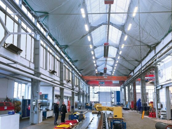 Große industrielle Werkhalle mit Arbeitern und Maschinen.