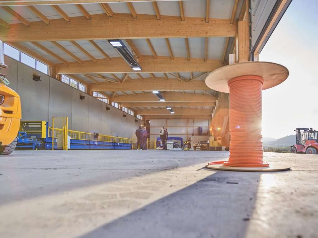 Industriehalle mit Kabelrolle und Arbeitern im Sonnenlicht