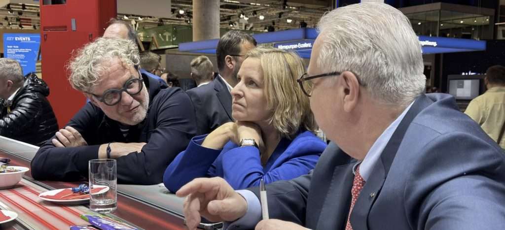 Folk diskuterer ved et messearrangement ved bordet.