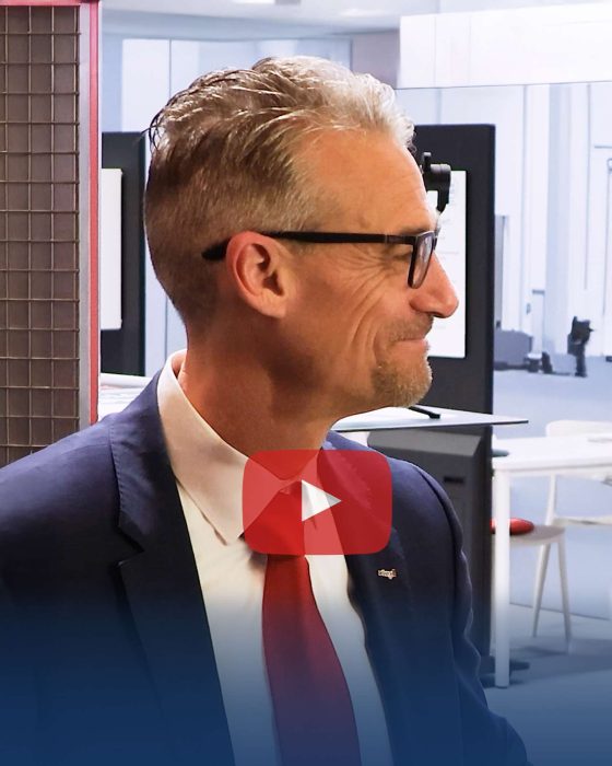 Mann mit Brille lächelt in modernem Büro