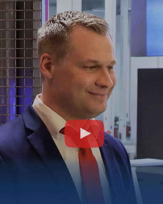 Man in suit smiles in front of YouTube icon
