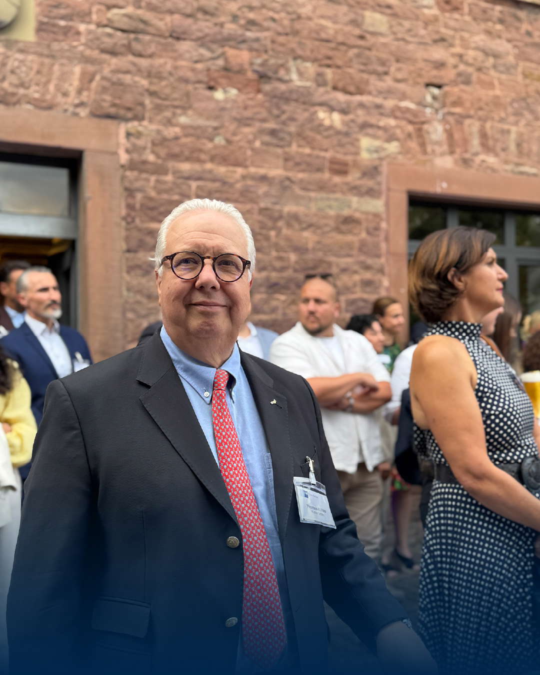 Iäkäs herrasmies puvussa historiallisen rakennuksen edessä