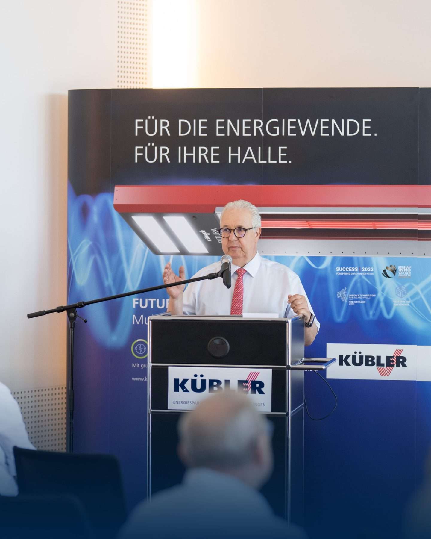 Мужчина читает лекцию об энергетическом переходе на мероприятии Kübler