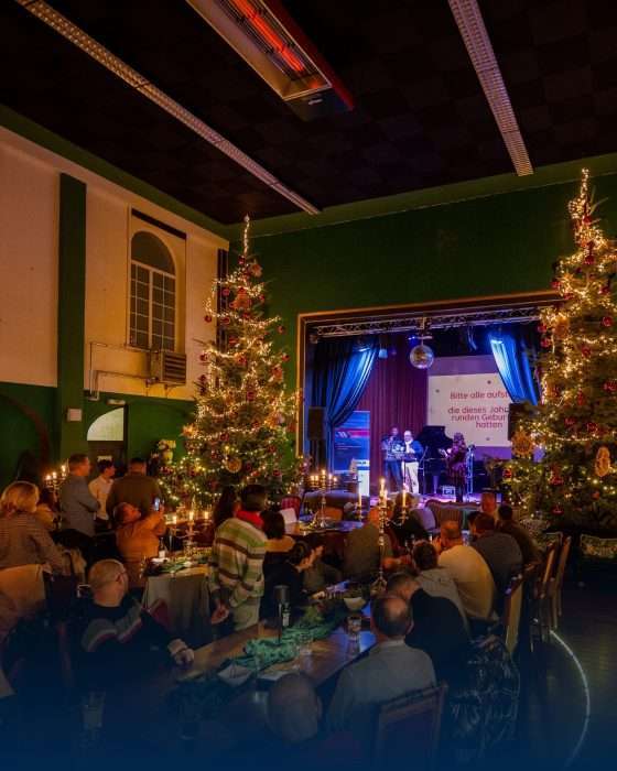 Weihnachtsfeier mit Bühne und geschmückten Tannenbäumen