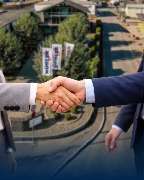 Üzletemberek kezet ráznak a cég épülete előtt