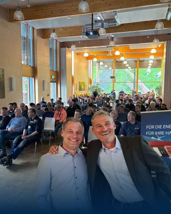 Zwei Männer vor Publikum in Veranstaltungshalle