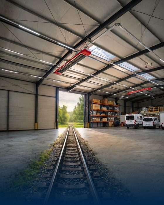 Teollisuushalli, jossa on kiskoja, telineitä ja kuljetuskalustoa