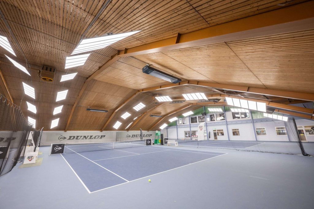 Indoor-Tennisplatz mit Holzdecke und Oberlichtern