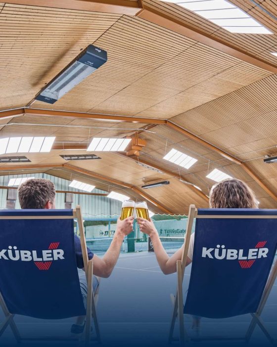 Et par skåler med øl i solstoler under KÜBLERs infrarøde varme i en oppvarmet tennishall
